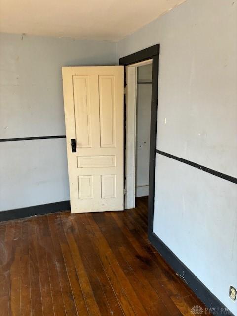 empty room featuring wood-type flooring and baseboards