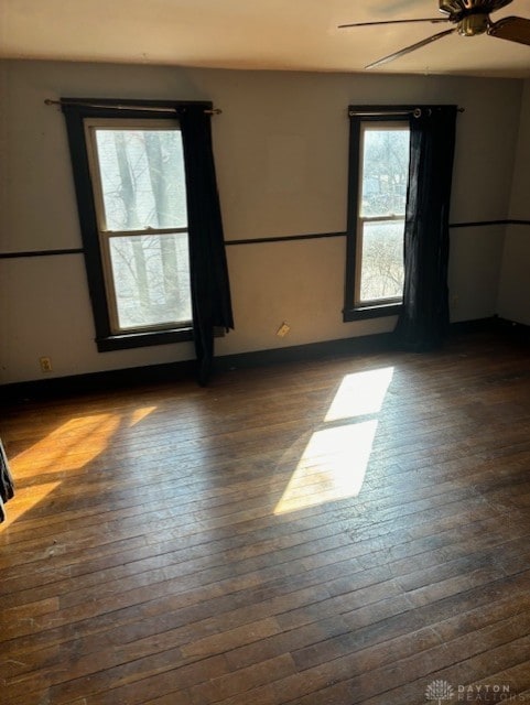 empty room with dark wood finished floors and a ceiling fan