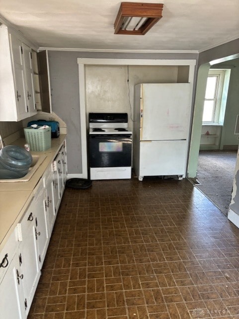 kitchen featuring range with electric cooktop, a sink, freestanding refrigerator, and white cabinetry