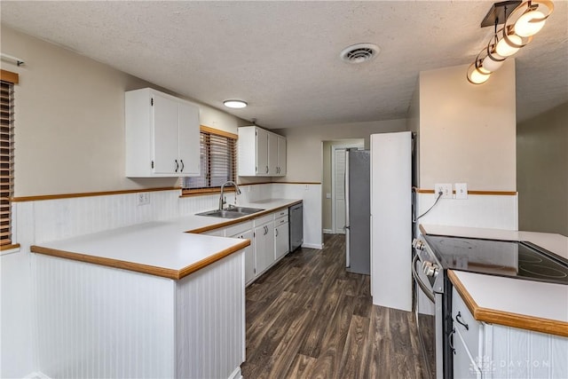 kitchen with dark wood finished floors, stainless steel appliances, visible vents, a sink, and a textured ceiling