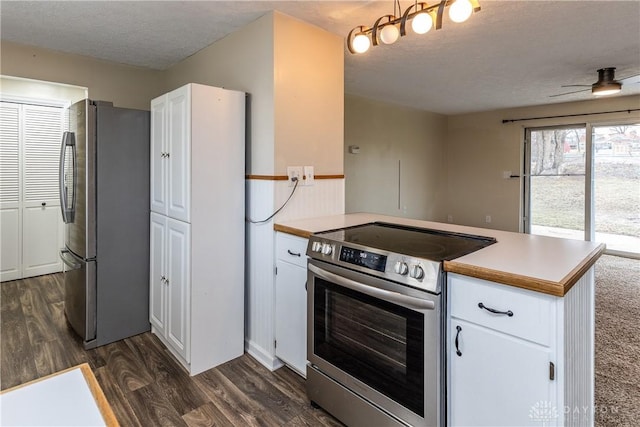 kitchen featuring dark wood finished floors, appliances with stainless steel finishes, a peninsula, light countertops, and white cabinetry