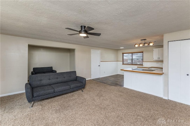 living area with a ceiling fan, dark carpet, and a textured ceiling