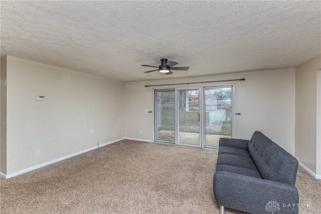 unfurnished room with a textured ceiling, carpet floors, a ceiling fan, and baseboards