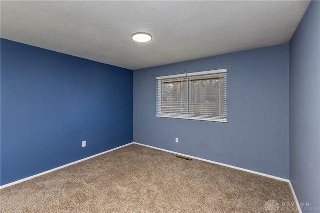 unfurnished room featuring a textured ceiling, carpet floors, visible vents, and baseboards