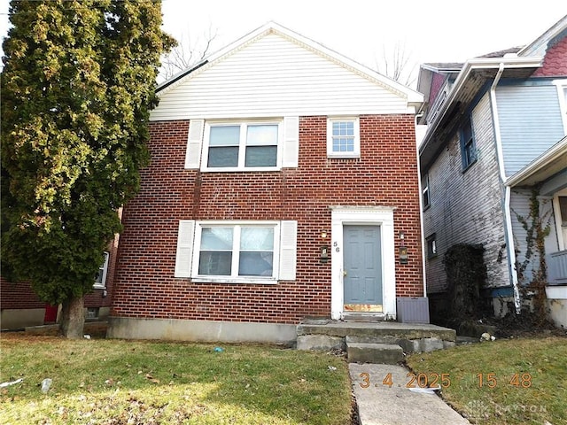 traditional home with brick siding and a front lawn