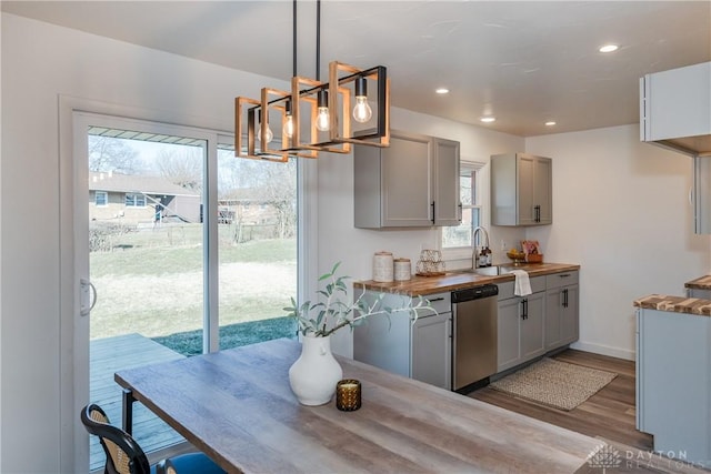 kitchen featuring dishwasher, butcher block counters, wood finished floors, and gray cabinetry