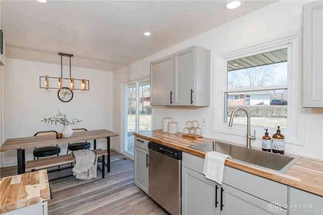 kitchen with butcher block countertops, light wood-style flooring, a sink, and stainless steel dishwasher