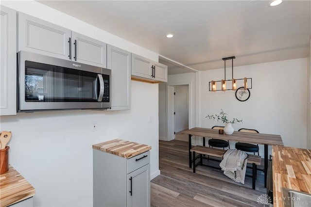 kitchen with stainless steel microwave, pendant lighting, recessed lighting, wood finished floors, and wood counters