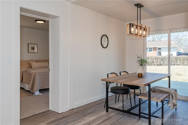 dining area with baseboards, a notable chandelier, and wood finished floors