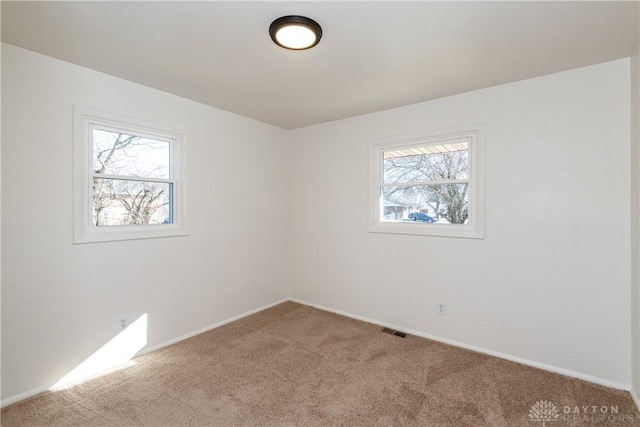 carpeted spare room with visible vents and baseboards