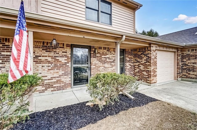 doorway to property with brick siding, driveway, and an attached garage