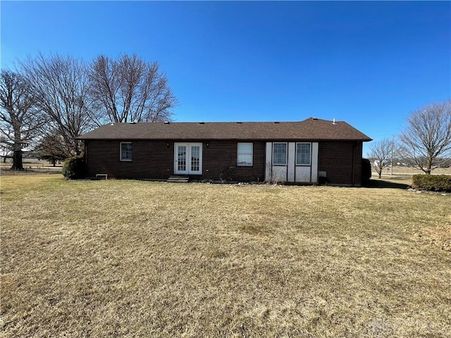 back of property with entry steps, brick siding, a lawn, and french doors