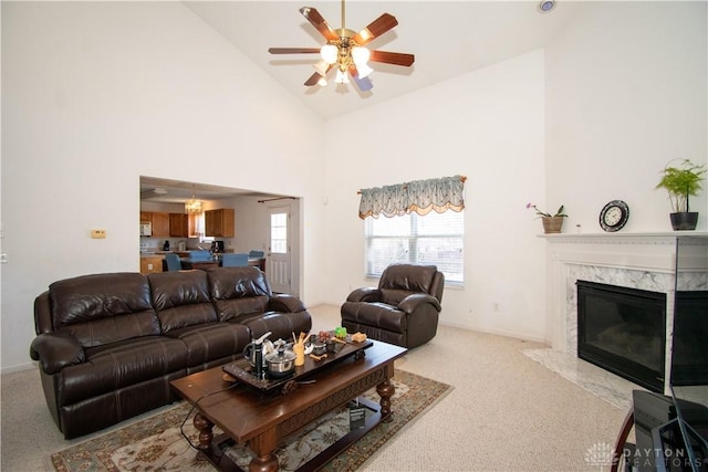 living room featuring baseboards, light colored carpet, ceiling fan, high vaulted ceiling, and a high end fireplace