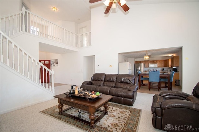 living room featuring stairs, baseboards, a towering ceiling, and a ceiling fan