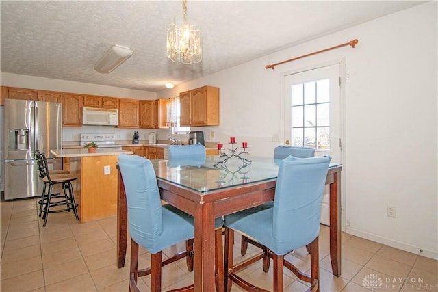 dining area featuring light tile patterned floors, a textured ceiling, a chandelier, and baseboards