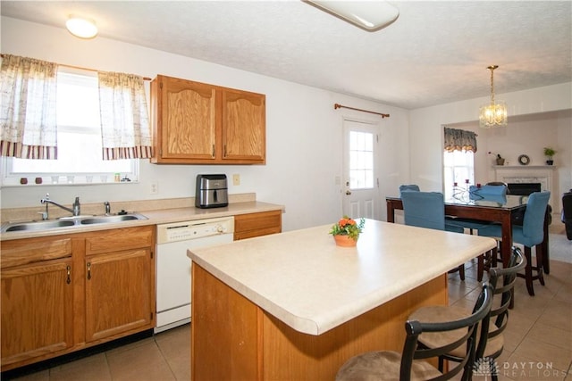 kitchen with dishwasher, a breakfast bar area, light countertops, a fireplace, and a sink