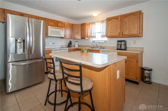 kitchen featuring white appliances, light countertops, a sink, and light tile patterned flooring