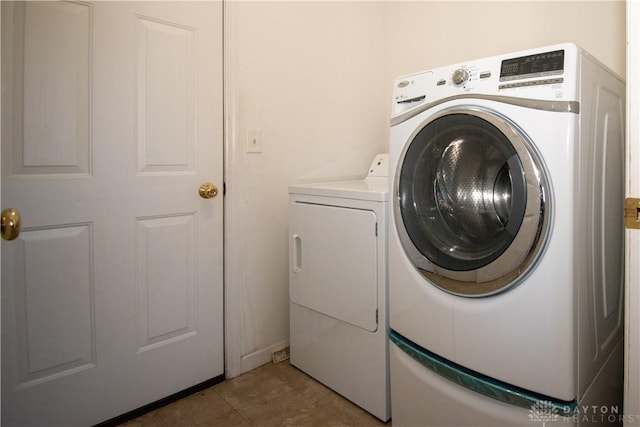 washroom with laundry area, washer and clothes dryer, and tile patterned flooring