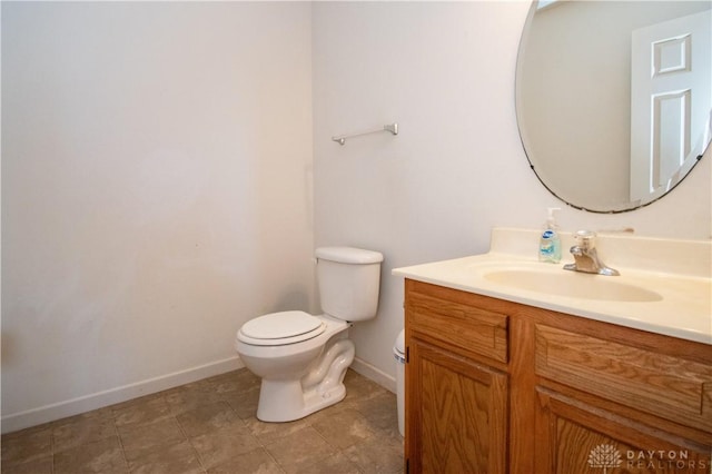 half bathroom featuring toilet, tile patterned flooring, baseboards, and vanity