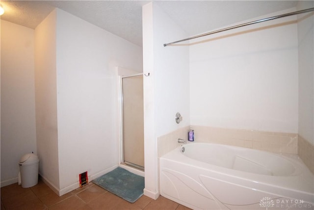 bathroom with a textured ceiling, a stall shower, a bath, and tile patterned floors