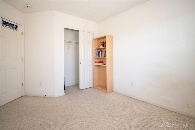 unfurnished bedroom featuring carpet, a closet, and baseboards