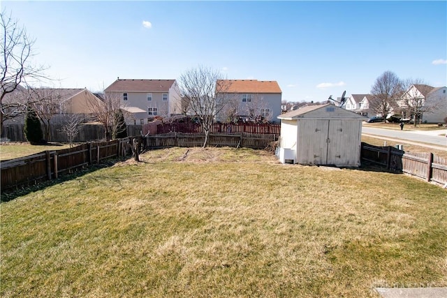 view of yard featuring a storage unit, an outdoor structure, a fenced backyard, and a residential view