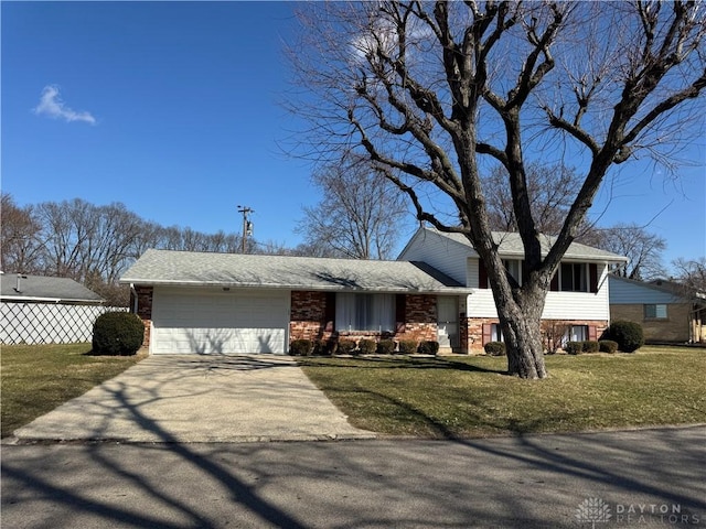 tri-level home with a garage, concrete driveway, fence, a front lawn, and brick siding