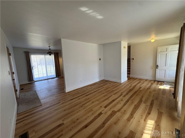 unfurnished room featuring baseboards, visible vents, and light wood finished floors