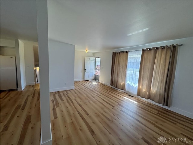 unfurnished living room featuring light wood finished floors and baseboards