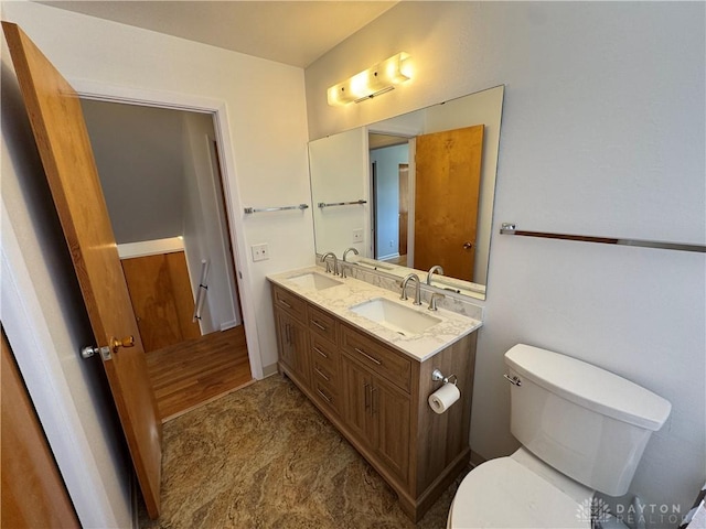 bathroom featuring toilet, double vanity, and a sink