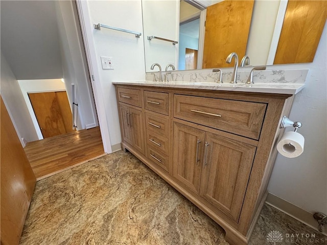 bathroom featuring double vanity, baseboards, and a sink