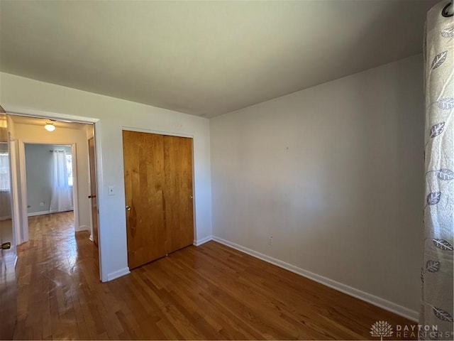 unfurnished bedroom featuring a closet, baseboards, and wood finished floors