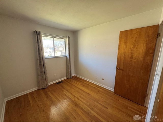 empty room with light wood-type flooring, baseboards, and visible vents