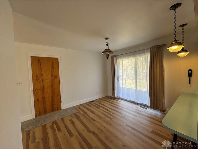 unfurnished dining area with visible vents, baseboards, and wood finished floors