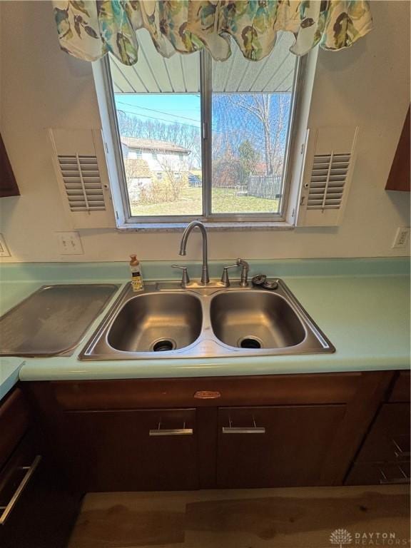 interior details featuring light countertops, a sink, and dark brown cabinetry