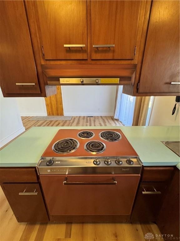 kitchen featuring cooktop, light countertops, light wood finished floors, and extractor fan