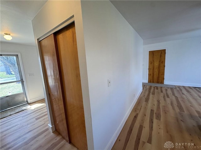 hallway featuring light wood-style flooring and baseboards