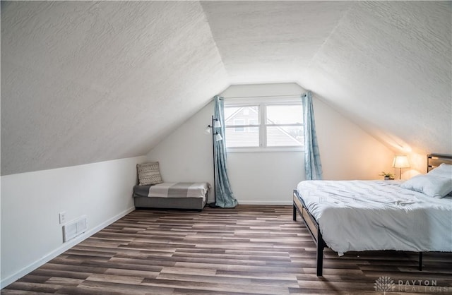 bedroom featuring baseboards, visible vents, a textured ceiling, and wood finished floors