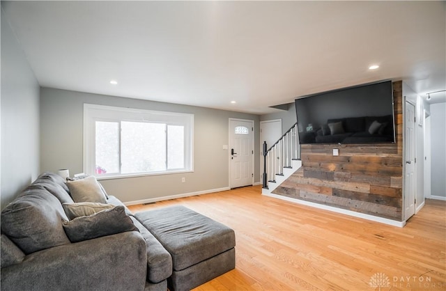 living room featuring light wood-type flooring, recessed lighting, baseboards, and stairs