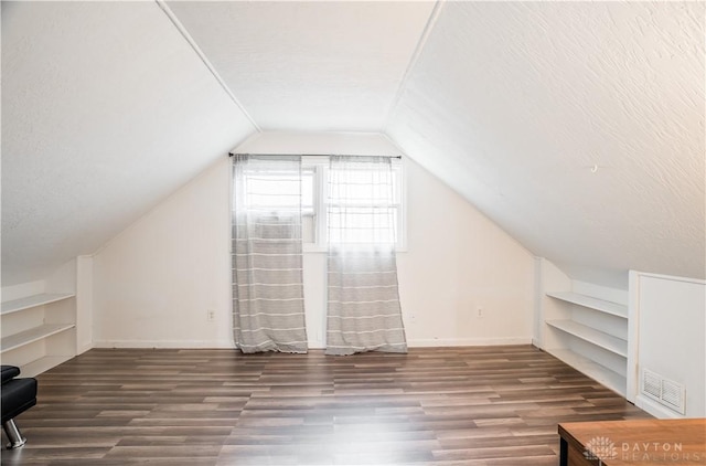 bonus room with lofted ceiling, a textured ceiling, wood finished floors, visible vents, and baseboards