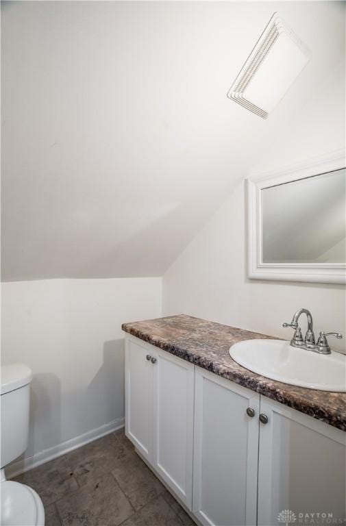 bathroom featuring toilet, baseboards, lofted ceiling, and vanity