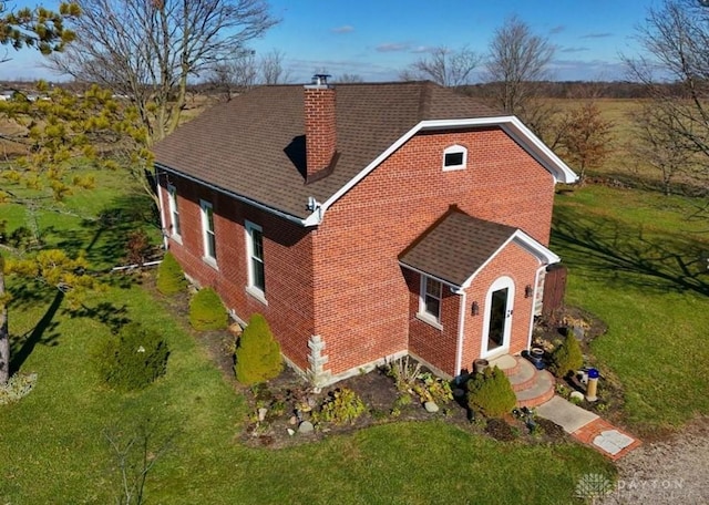 view of front facade featuring a front lawn, brick siding, and a chimney