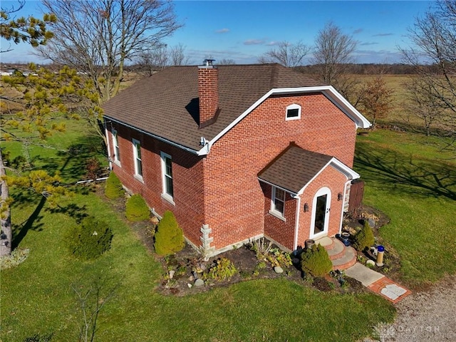 view of front of house with a front lawn, a chimney, a shingled roof, and brick siding