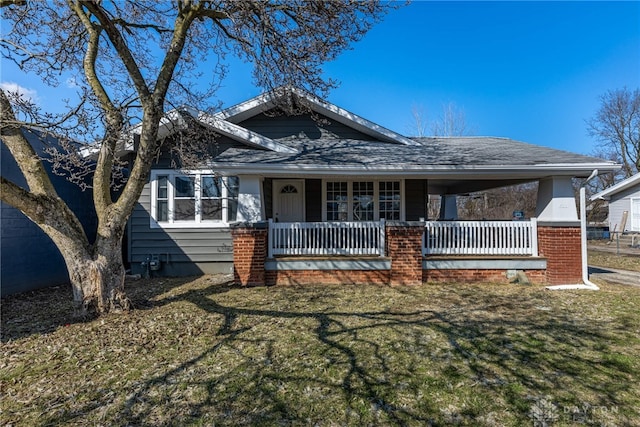 view of front of house featuring a shingled roof, covered porch, a carport, and a front lawn