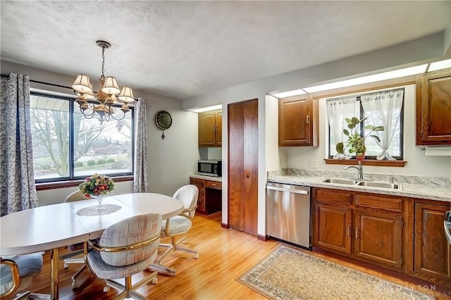 kitchen with appliances with stainless steel finishes, light wood-style floors, a chandelier, pendant lighting, and a sink