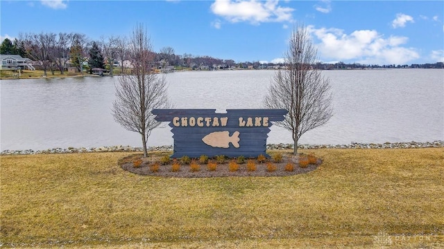 community / neighborhood sign with a water view and a lawn