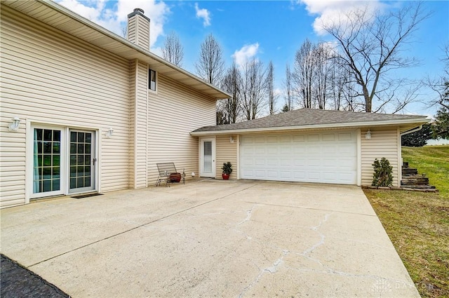 view of side of home featuring a garage, driveway, and a chimney