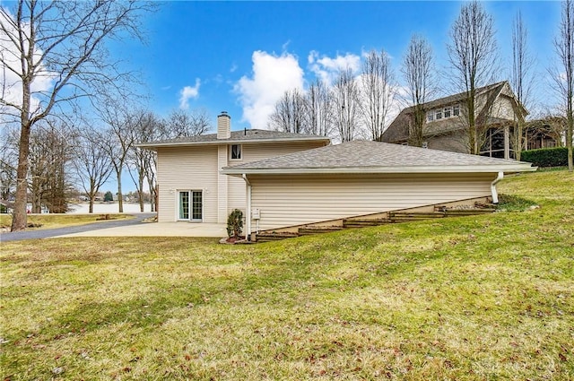 back of house with a chimney, a lawn, and a patio