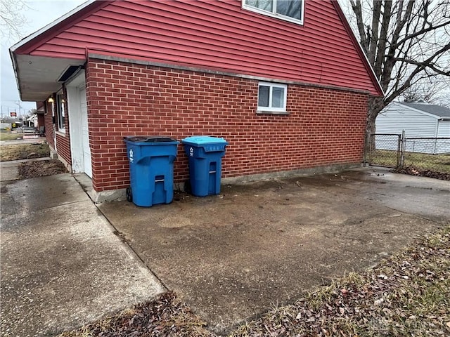 view of side of property with a gate, brick siding, and fence