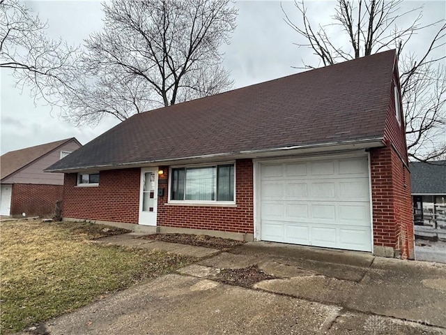 view of front facade with driveway, an attached garage, brick siding, and roof with shingles